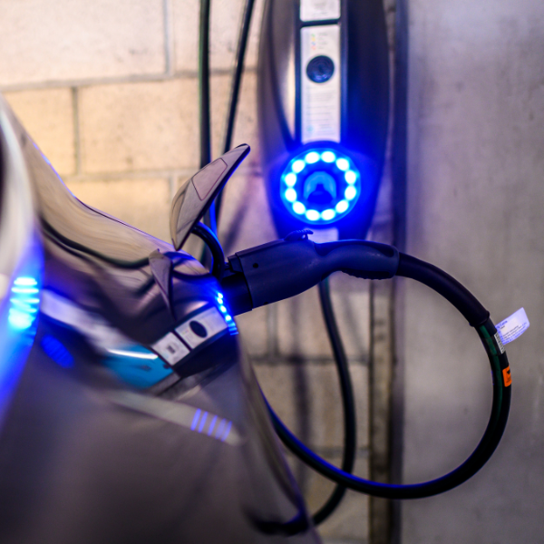 An electric vehicle plugged into a Level 2 charger in a garage.