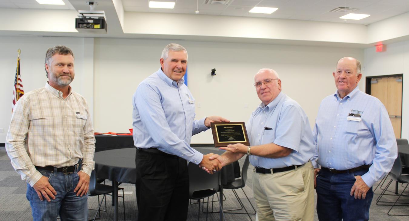 Oklahoma Farm Bureau Board Member Jim Meek, accompanied by Farm Bureau Agent Jim Hall and Board Member Larry Harvey, presents an award to ECOEC General Manager Tim Smith. 