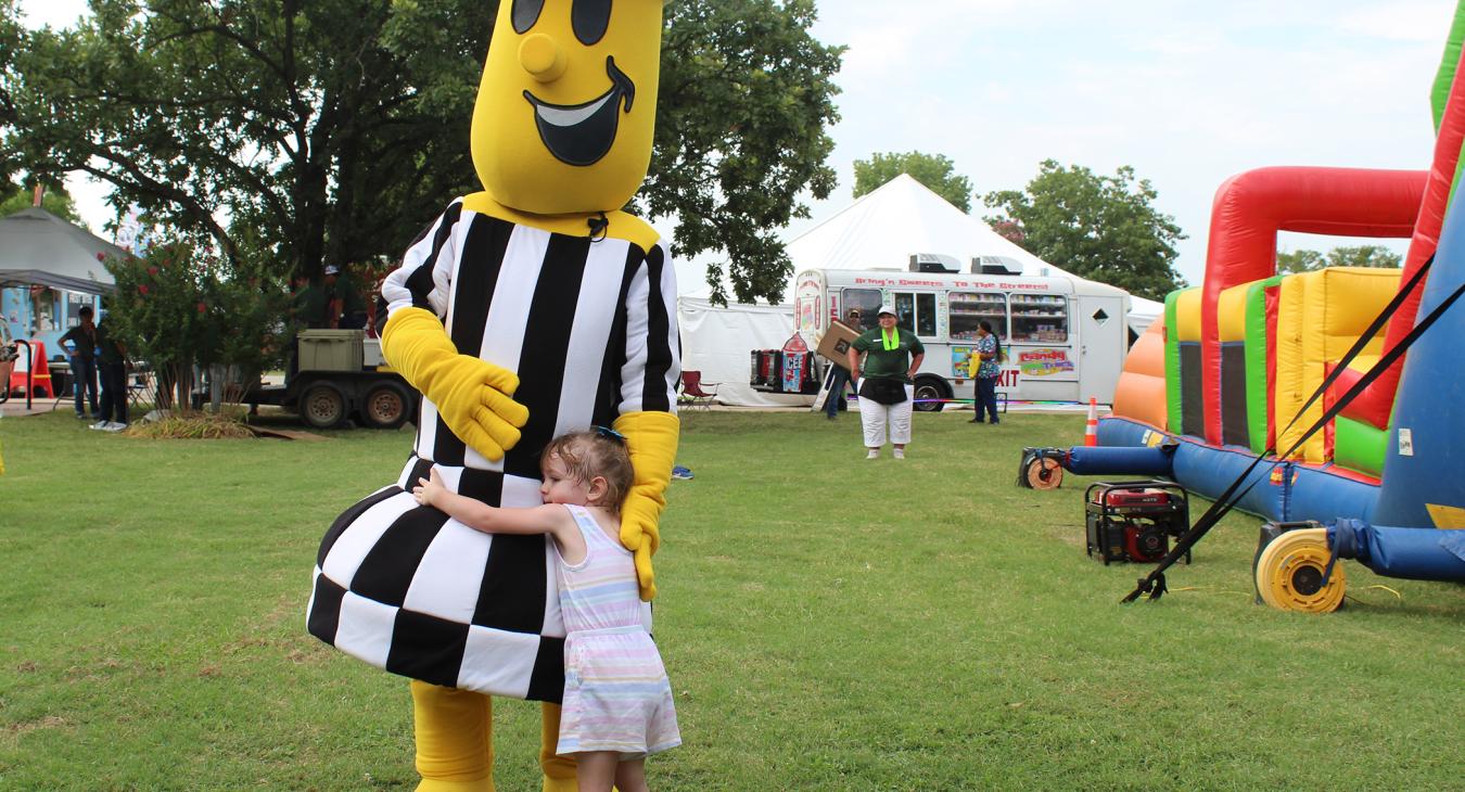 Willie Wiredhand Mascot hugs child at Annual Meeting